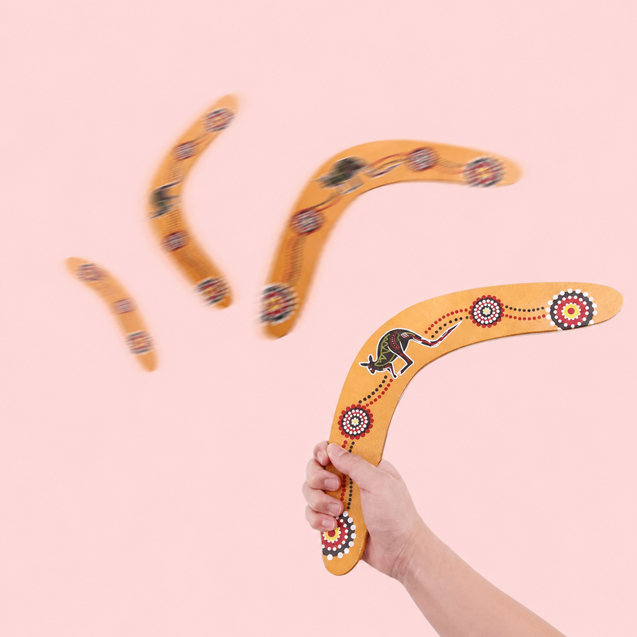 Decorative boomerang with Aboriginal art design held by a hand.