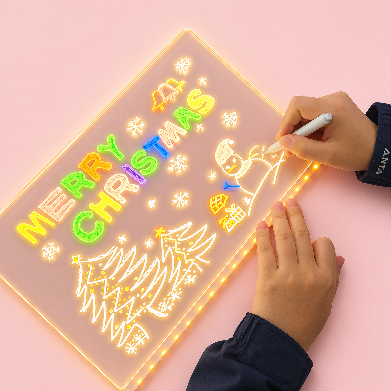 Person drawing on a light-up Christmas-themed board with colorful letters and graphics.