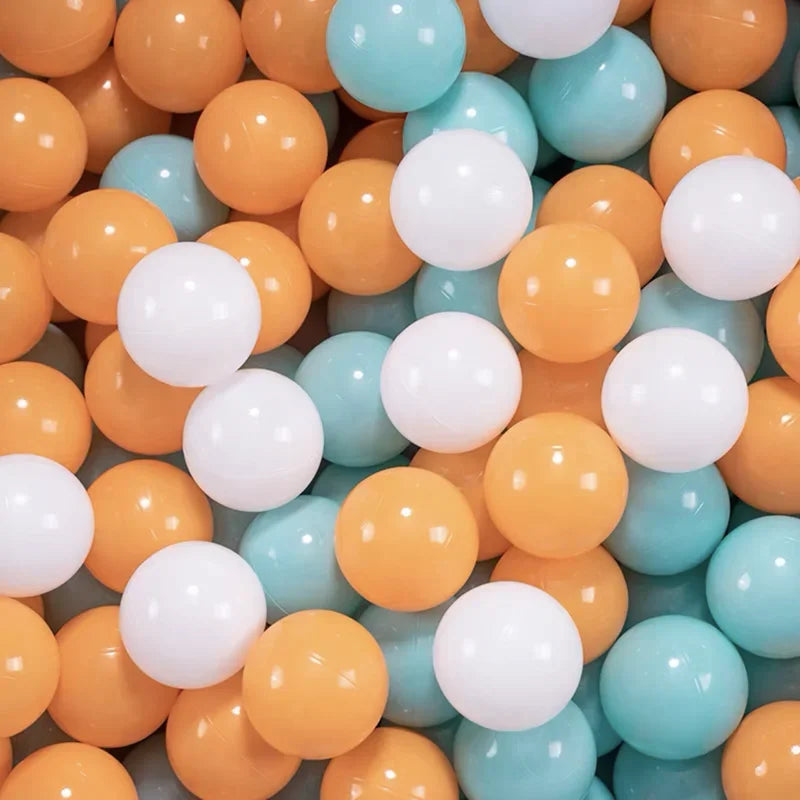 Close-up of colorful plastic balls including orange, white, and teal for tent ball pitt
