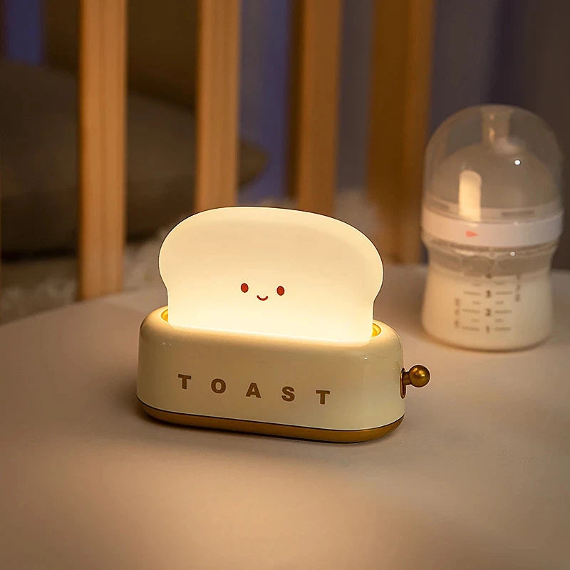 Toy toaster with a smiling face on a surface next to a baby bottle.