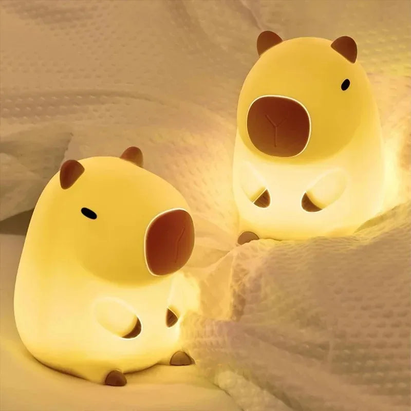 Two yellow animal-shaped Cute Capybara night lights on a soft fabric background