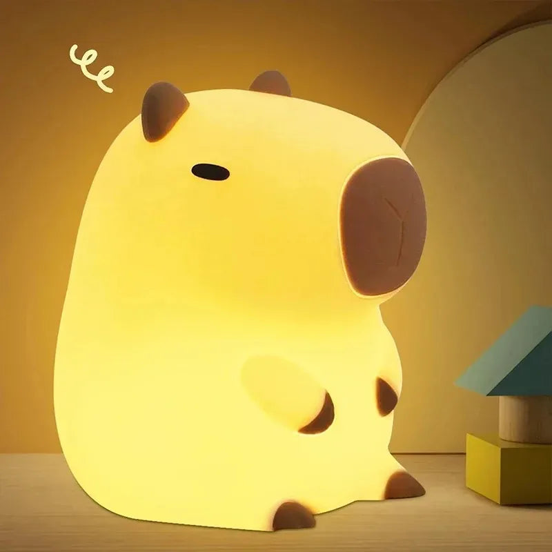Cute animal-shaped Cute Capybara night light on a wooden surface with a warm yellow background