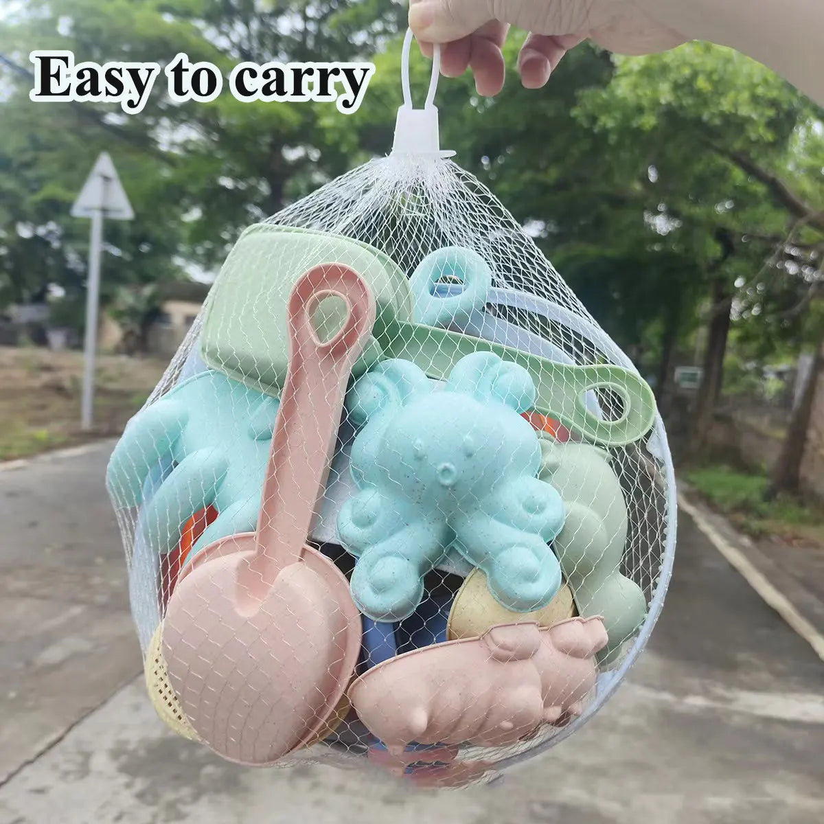 Set of soft toys in a mesh bag with text 'Easy to carry' on a blurred outdoor background.