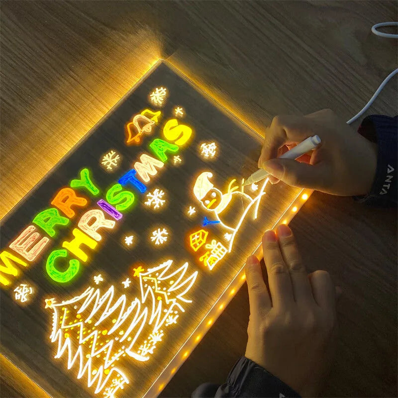 Person drawing on a light-up Christmas-themed board with colorful letters and a snowman.