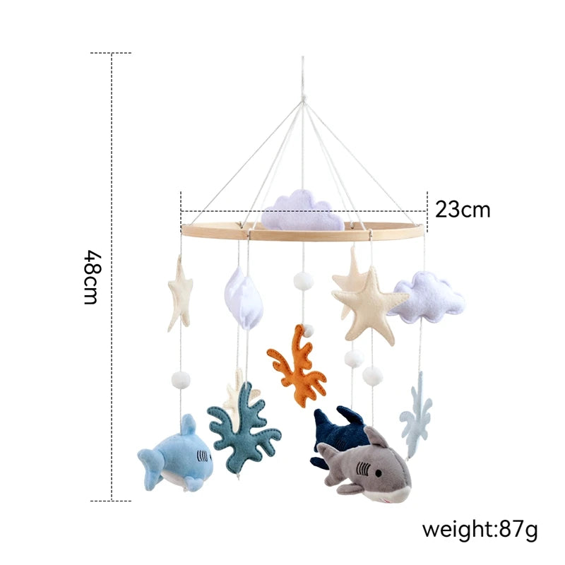 Baby crib/cot mobile with sea-themed decorations including sharks, fish, and coral, with measurements and weight displayed.