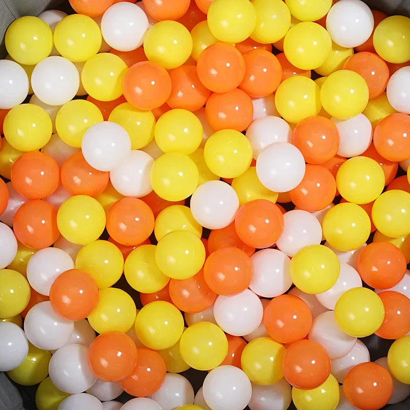 Close-up of colorful plastic balls including yellow, orange, and white for a tent ball pitt