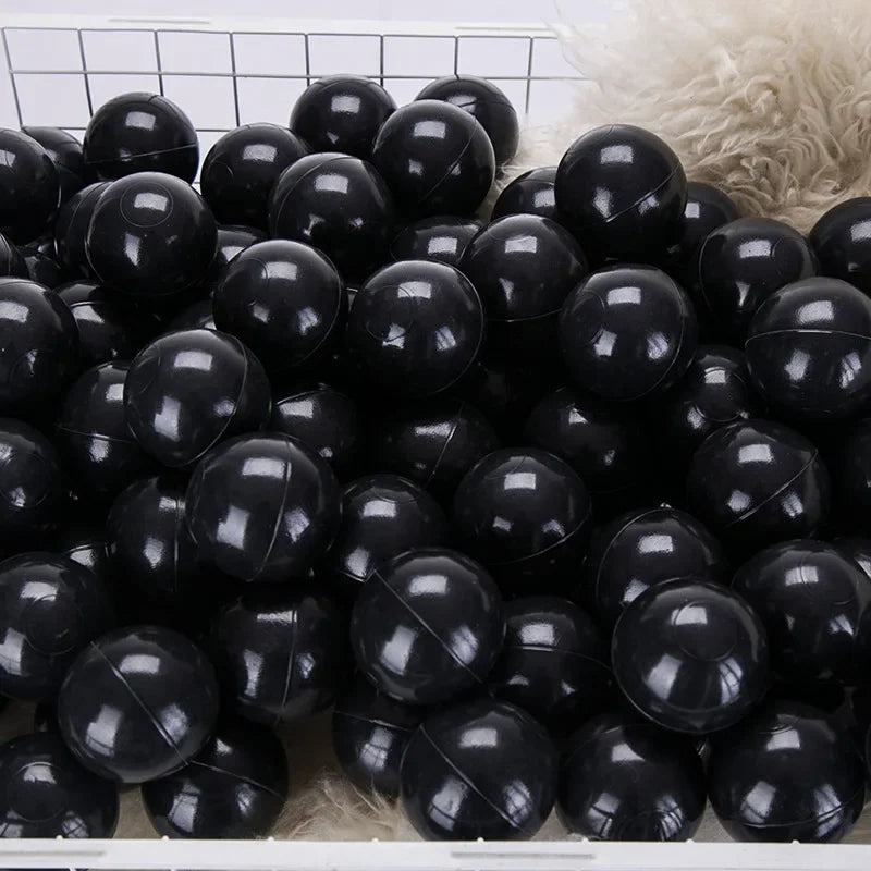 Pile of black balls on a textured surface with a grid pattern in the background