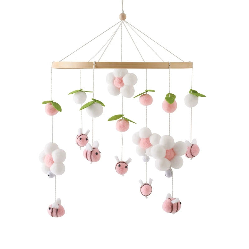 Decorative hanging baby crib mobile with flowers and pink bees on a white background