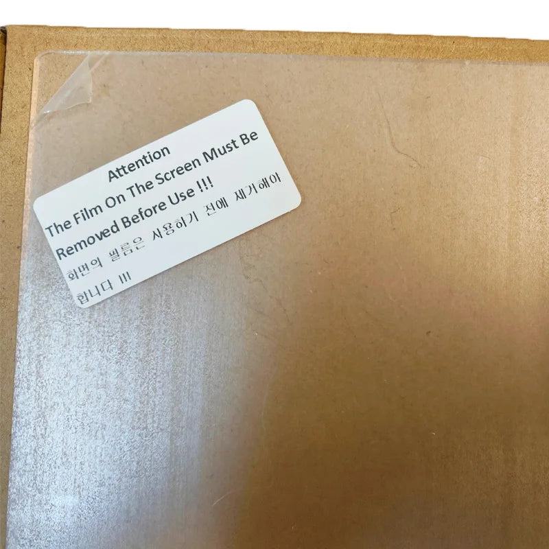 Clear screen protector on a cardboard box with a warning label.
