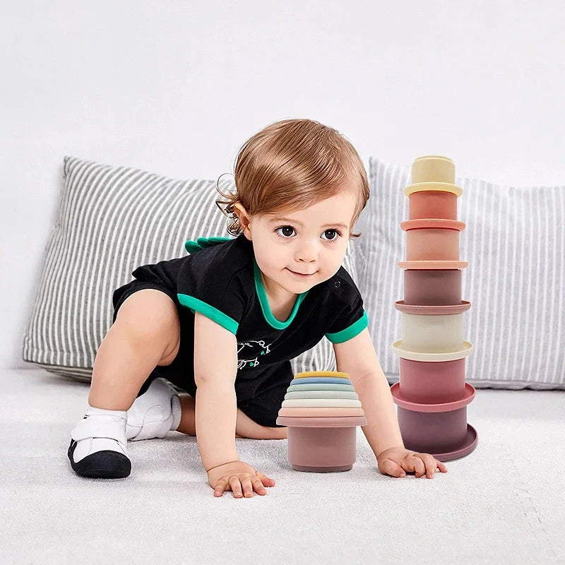 Child playing with colorful stacking cups on a light-colored surface.