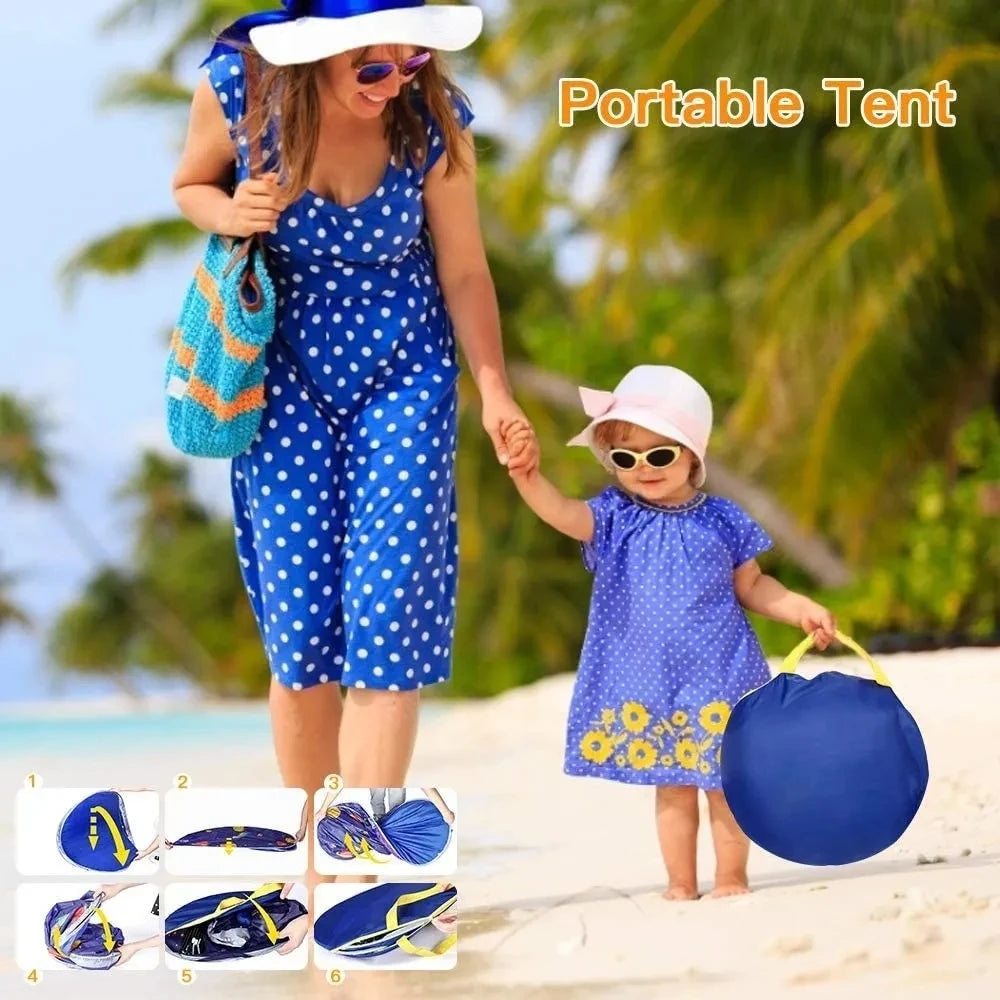 Woman and child in matching blue outfits with a portable tent on a beach.