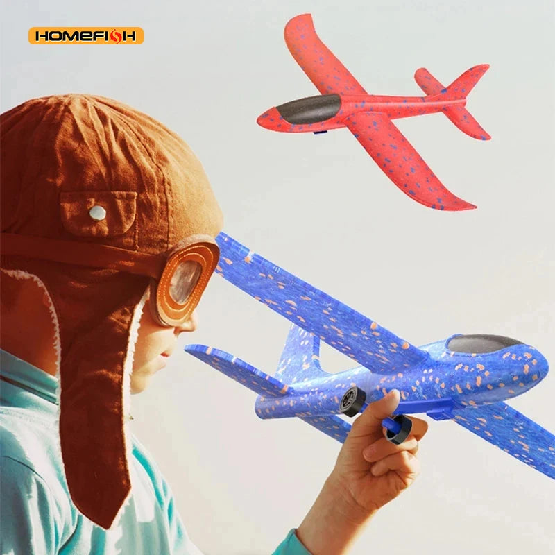 Child wearing a vintage helmet and goggles holding a blue airplane toy with a red airplane in the background.